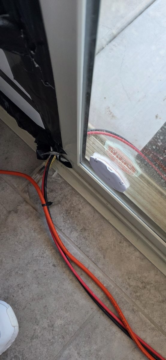 Solar PV cables passing through a sealed sliding glass door into the house